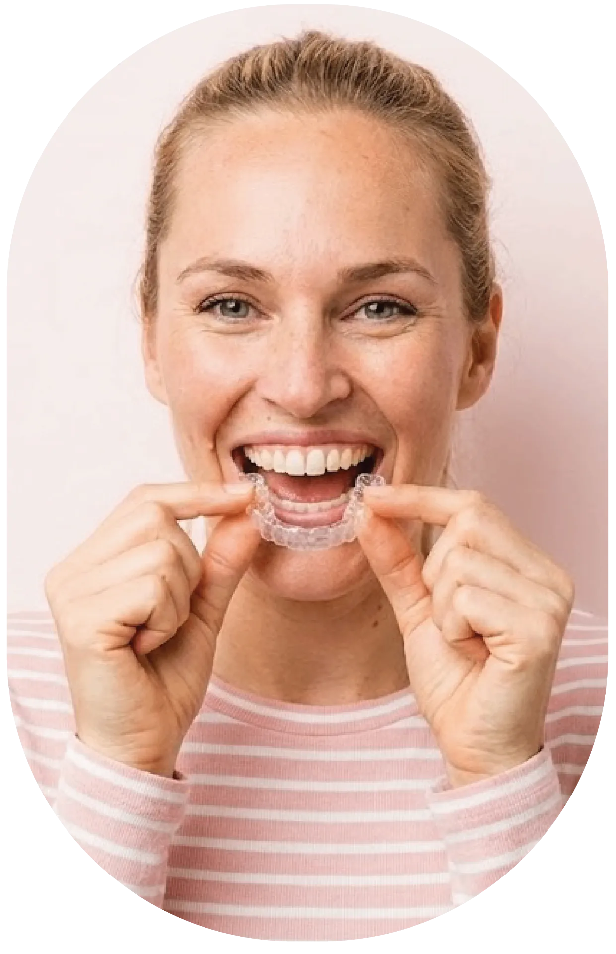 Smiling patient holding a clear Invisalign aligner